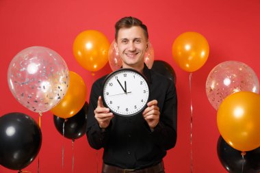 Yuvarlak saat parlak kırmızı arka plan hava balonu üzerinde tutarak siyah klasik gömlek yakışıklı genç adam. St. Valentine's, Dünya Kadınlar günü, mutlu yeni yıl, Doğum günü mockup tatil parti konsept