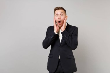 Putting eller yanaklarda, gri duvar arka plan üzerinde izole yüz şok genç iş adamı ağız seyir şaşırttı, geniş açık tutmak. Başarı kariyer servet iş kavramı. Kopyalama alanı alay