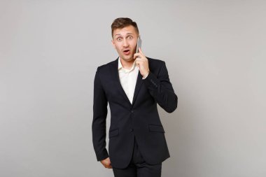 Gri arka plan üzerinde izole konuşma iletken ağız açık tutarak, cep telefonu üzerinde konuşurken sürpriz arıyor şok iş adamı. Başarı kariyer servet iş kavramı. Kopyalama alanı alay
