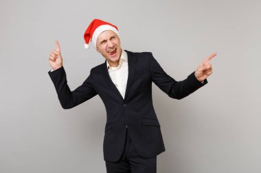 Takım, dizin bir kenara gri arka plan üzerinde izole parmakları işaret Noel şapka neşeli genç iş adamı. Başarı kariyer servet iş. Mutlu yeni yıl 2019 kutlama tatil parti konsept