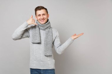 Gri süveterli yakışıklı genç adam, beni bir kenara gri arka plan üzerinde izole el işaret ara, eşarp gibi telefon jest yapıyor diyor. Sağlıklı yaşam, insanlar samimi duygular, soğuk sezon kavramı