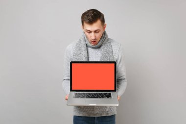 Kazaklı, boş boş ekran gri arka plan üzerinde izole ile dizüstü pc bilgisayar üzerinde seyir eşarp genç adam. Sağlıklı yaşam, online tedavi danışmanlık, soğuk sezon kavramı. Kopyalama alanı alay