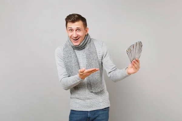 グレーのセーターに興奮して幸せな若い男はスカーフ ドル紙幣 灰色の背景に分離された資金の多くの束に手の形です 健康的なライフ スタイル 心から感情の寒い季節の概念 — ストック写真