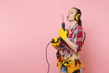 Enerji seksi tamirci kadın eldiven, gürültü yalıtımlı kulaklıklar, Seti Araçları, pembe arka plan izole elektrikli matkap tutan araçların tam kemer. Kadın erkek iş. Yenileme kavramı