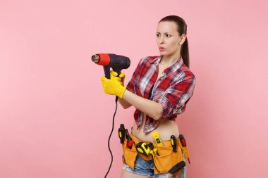 Genç güzel ev erkeği kadın ekose gömlek, kot şort, kit araçları kemer, pembe arka plan izole güç ısı silah tutan çeşitli araçların tam eğlenceli. Kadın erkek iş. Yenileme kavramı