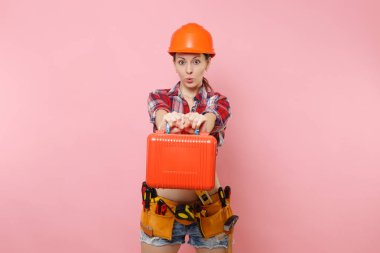 Güçlü genç tamirci kadın portakal kask, ekose gömlek, kot şort, aletleri, dolu, pembe arka plan izole araç seti araçları kemer. Kadın erkek iş. Yenileme işgal kavramı