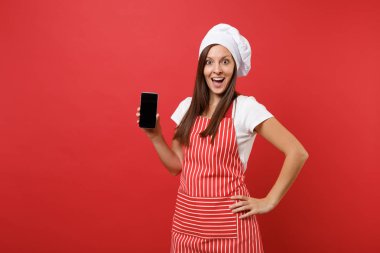 Ev hanımı kadın şef aşçı ya da çizgili önlük t-shirt toque şefler şapkalı kırmızı duvar arka plan üzerinde izole baker. Kadın cellphone yükselme içerik için boş ekran ile tutun. Kopyalama alanı kavramı alay