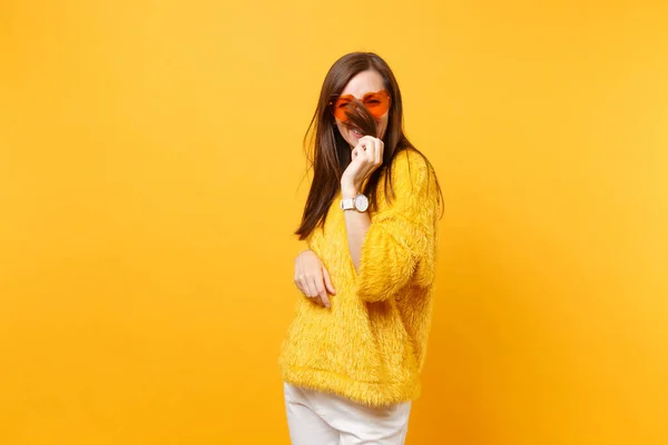 微笑滑稽的年轻女子在毛皮毛衣和心脏橙色眼镜举行 覆盖面与头发查出在明亮的黄色背景 人们真诚的情感 生活方式的理念 广告区 — 图库照片