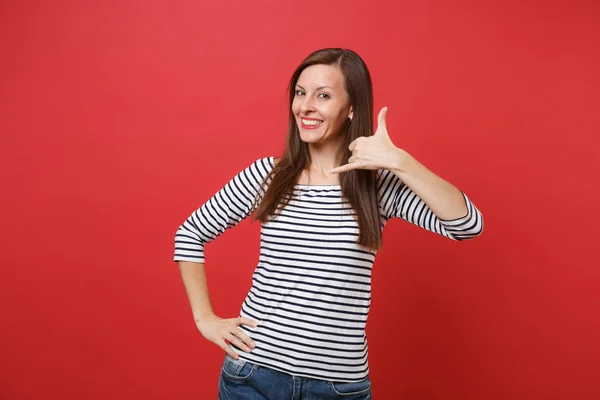 Smiling young woman doing phone gesture like says: call me back with hand, fingers like talking on the telephone isolated on red background. Communicating, people sincere emotions, lifestyle concept