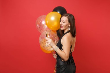 Siyah elbise kutlayarak çekici kadın yan görünüm kırmızı zemin üzerine izole balonları hava kadeh şampanya, holding. St. Valentine's Day, mutlu yeni yıl Doğum günü mockup tatil parti konsept