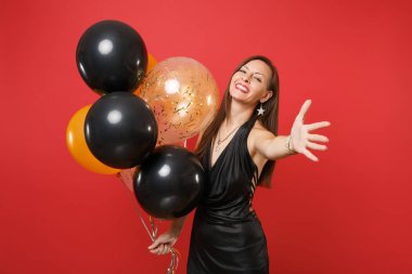 Gülümseyen hava balonları, kutlama tutarak fotoğraf makinesinde işaret eden bir ele izole kırmızı zemin üzerine siyah elbiseli güzel genç kadın. Sevgililer günü mutlu yeni yıl Doğum günü mockup tatil parti konsept