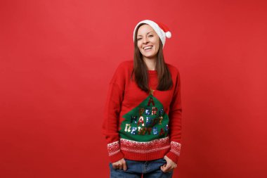 Noel Baba kız örme kazak gülüyor, ceplerinde elele Noel şapka parlak kırmızı duvar arka plan üzerinde izole. Mutlu yeni yıl 2019 kutlama tatil parti kavramı. Kopyalama alanı alay