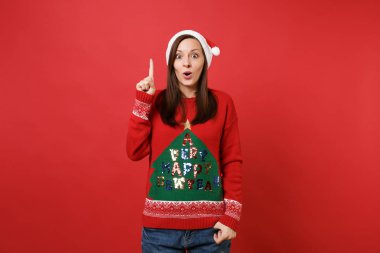 Heyecanlı genç Noel Baba kız holding parmağı yukarıya ile harika yeni fikir, ağzı açık, sürpriz seyir tutmak izole kırmızı duvar arka plan üzerinde. Mutlu yeni yıl 2019 kutlama tatil parti konsept
