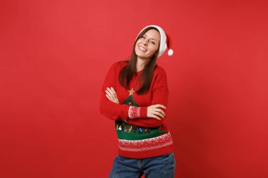 Genç ve güzel Santa parlak kırmızı duvar arka plan üzerinde katlanmış elele örme kazak Noel şapkalı kız izole gülümseyerek. Mutlu yeni yıl 2019 kutlama tatil parti kavramı. Kopyalama alanı alay