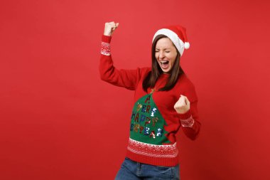 Kazanan kırmızı zemin üzerine izole gibi çok memnun genç Noel Baba kız yumruğunu kenetlenmesi çığlık Noel şapka kapalı gözlerle. Mutlu yeni yıl 2019 kutlama tatil parti kavramı. Kopyalama alanı alay