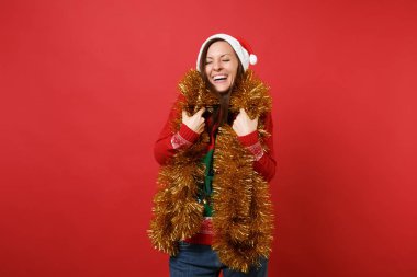 Noel Baba kız altın garland ile Noel şapkalı gülüyor, gözlerini tutmak tinsel izole üzerinde parlak kırmızı arka plan kapalı. Mutlu yeni yıl 2019 kutlama tatil parti kavramı. Kopyalama alanı alay