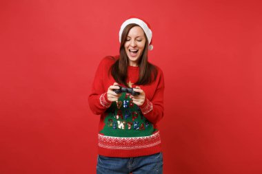 Örme kazak, joystick ile bilgisayar oyunu oynamak Noel şapka içinde neşeli Noel Baba kız kırmızı duvar arka plan üzerinde izole. Mutlu yeni yıl 2019 kutlama tatil parti kavramı. Kopyalama alanı alay