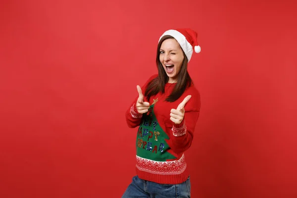 스웨터 크리스마스 모자에 빨간색 배경에 깜박이 카메라에 손가락을 가리키는에서 2019 — 스톡 사진