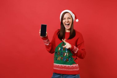 Kırmızı zemin üzerine izole boş boş ekran ile işaret parmağı cep telefonu çığlık neşeli Noel Baba kız. Mutlu yeni yıl 2019 kutlama tatil parti kavramı. Kopyalama alanı alay