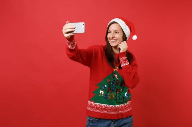 Çarpıcı neşeli Noel Baba içindeki genç kız Noel şapka alarak selfie cep telefonu parlak kırmızı zemin üzerine izole atış yapıyor. Mutlu yeni yıl 2019 kutlama tatil parti kavramı. Kopyalama alanı alay