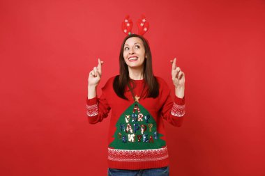 Eğlenceli neşeli Noel Baba kız dekoratif geyik boynuzları ararken, özel an için bekleyen koruma parmak üzerinde izole kırmızı arka plan çarpı işareti. Mutlu yeni yıl 2019 kutlama tatil parti konsept