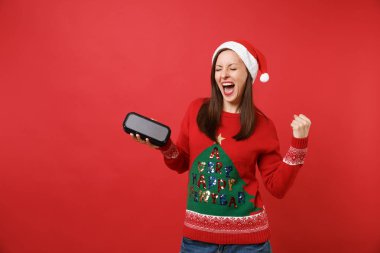 Taşınabilir kablosuz bluetooth müzik hoparlör tutan kazanan jest yapıyor neşeli Noel Baba kız kırmızı zemin üzerine izole. Mutlu yeni yıl 2019 kutlama tatil parti kavramı. Kopyalama alanı alay