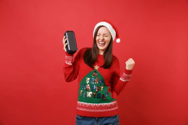 Mutlu genç Noel Baba kız kenetlenmesi yumruk gibi kazanan, taşınabilir kablosuz bluetooth müzik hoparlör izole kırmızı zemin üzerine tutun. Mutlu yeni yıl 2019 kutlama tatil parti kavramı. Kopyalama alanı alay