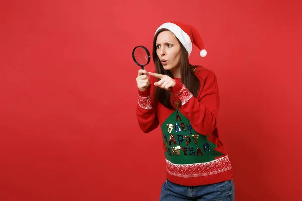 Förbryllat Santa Flicka Tittar Uppmärksamt Bakom Förstoringsglas Pekar Pekfinger Isolerad — Stockfoto