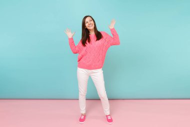 Tam uzunlukta örme gül kazaklı gülümseyen genç kadın portresi, beyaz parlak pembe mavi pastel duvar arka planda Studio izole poz pantolon. Moda yaşam tarzı kavramı. Kopyalama alanı alay