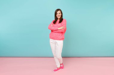 Tam uzunlukta örme gül kazaklı gülümseyen genç kadın portresi, beyaz parlak pembe mavi pastel duvar arka planda Studio izole poz pantolon. Moda yaşam tarzı kavramı. Kopyalama alanı alay