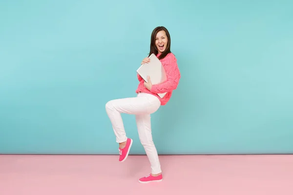 Full length portrait of woman in knitted rose sweater white pants holding laptop pc computer isolated on bright pink blue pastel wall background in studio Fashion lifestyle concept Mock up copy space