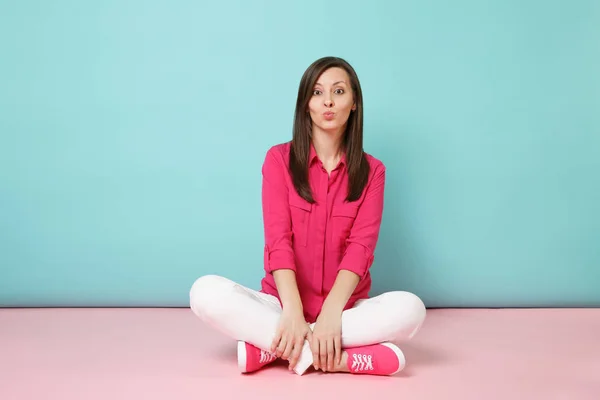 纵向微笑的年轻女子在玫瑰衬衫衬衫 白色裤子坐在地板上查出明亮的粉红色蓝色蜡笔墙背景工作室时尚生活方式概念 模拟复制空间 — 图库照片
