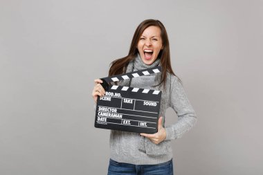 Gri süveterli çılgın genç kadın eşarp çığlık, klasik kara film gri arka plan üzerinde izole Klaket yapma tutarak. Sağlıklı moda yaşam tarzı, insanlar samimi duygular, soğuk sezon kavramı