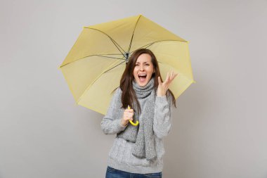 Gri süveterli, çığlık, eşarp sinir bozucu kadın gri arka plan üzerinde izole sarı şemsiye tutun eller, yayılıyor. Sağlıklı moda yaşam tarzı insanların duyguları soğuk sezon kavramı. Kopyalama alanı alay