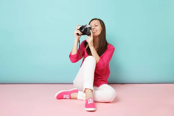 全长纵向年轻妇女在玫瑰色衬衫衬衫白色裤子坐在地板上保持相机查出粉红色蓝色蜡笔墙壁背景工作室 时尚生活理念 模拟复制空间 — 图库照片