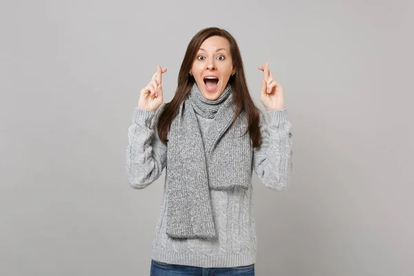兴奋的女人穿着灰色毛衣 围巾保持手指交叉 张大嘴巴 等待特殊的时刻隔离在灰色的背景 健康时尚生活方式 人的情绪 寒冷的季节概念 — 图库照片