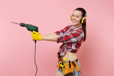 Enerji seksi tamirci kadın eldiven, gürültü yalıtımlı kulaklıklar, Seti Araçları, pembe arka plan izole elektrikli matkap tutan araçların tam kemer. Kadın erkek iş. Yenileme kavramı