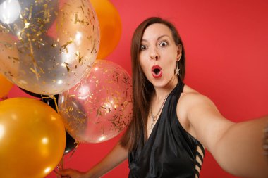 Selfie atış şok genç kız hava balonu parlak kırmızı zemin üzerine izole tutarak siyah elbise kutlayarak kapatın. St. Valentine's gün mutlu yeni yıl, Doğum günü mockup tatil parti konsept