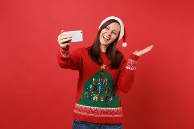 Neşeli Noel Baba kız alma selfie yapıyor Noel şapkalı bir kenara izole kırmızı zemin üzerine el işaret üstünde hareket eden telefon, vurdu. Mutlu yeni yıl 2019 kutlama tatil parti kavramı. Kopyalama alanı alay
