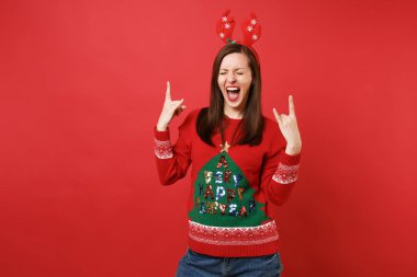 Eğlenceli çılgın Noel Baba kız dekoratif geyik boynuzları, çığlıklar, boynuzları jest gösterilen tarih izole kırmızı arka plan oturum heavy metal rock tasvir. Mutlu yeni yıl 2019 kutlama tatil parti konsept