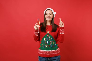 Parmak çarpı işareti gözler tutmak dilek yapma neşeli Noel Baba kız holding bardak şampanya kırmızı zemin üzerine izole kapalı. Mutlu yeni yıl 2019 kutlama tatil parti kavramı. Kopyalama alanı alay