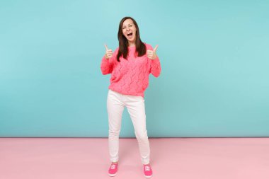 Tam uzunlukta örme gül kazaklı gülümseyen genç kadın portresi, beyaz parlak pembe mavi pastel duvar arka planda Studio izole poz pantolon. Moda yaşam tarzı kavramı. Kopyalama alanı alay