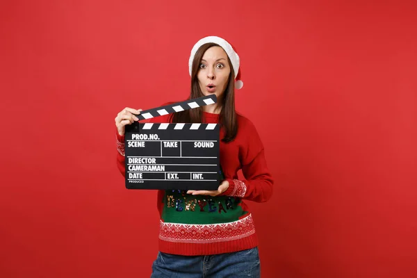 令人惊讶的年轻圣诞老人女孩张大嘴 拿着经典的黑色电影 在红色背景上孤立的隔板 快乐的新年2019年庆祝节日派对概念 模拟复制空间 — 图库照片