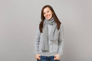 Genç kadın gri süveterli eşarp el ele tutuşsun gri duvar arka planda, stüdyo portre izole ceplerinde. Sağlıklı moda yaşam tarzı, insanlar samimi duygular, soğuk sezon kavramı. Kopyalama alanı alay