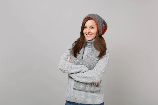 微笑的年轻女子在灰色毛衣帽子和围巾牵手折叠在灰色背景隔离在工作室 健康时尚生活方式的人真诚的情绪寒冷的季节概念 模拟复制空间 — 图库照片