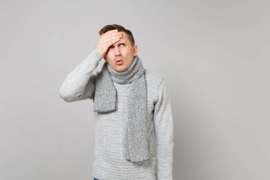 Gri süveterli Studio gri duvar arka plan üzerinde izole baş el koyarak eşarp meşgul genç adam. Sağlıklı moda yaşam tarzı insanların samimi duygular soğuk sezon kavramı. Kopyalama alanı alay