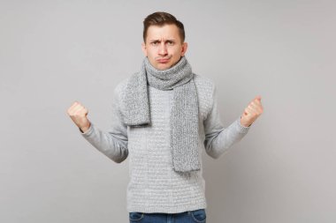 Söz konusu genç adam gri süveterli kenetlenmesi yumruk gri arka plan üzerinde stüdyo portre izole eşarp. Sağlıklı moda yaşam tarzı, insanlar samimi duygular, soğuk sezon kavramı. Kopyalama alanı alay