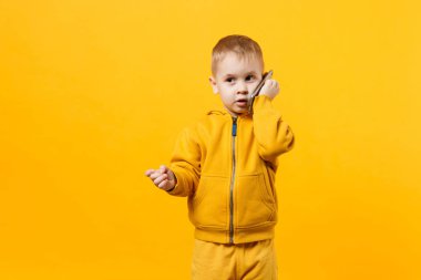 Küçük serin çocuk çocuk 3-4 yıl eski cep telefonu turuncu duvar arka planda, stüdyo portre izole konuşurken sarı giysili. Sorun çocuk ve becerikli alet. Yaşam tarzı kavramı. Kopyalama alanı alay