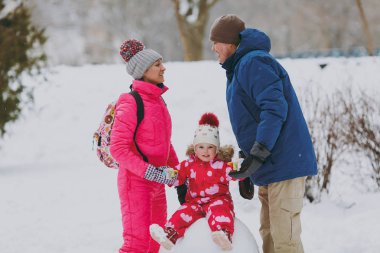 Mutlu aile kadın, adam kış sıcak giysiler ve kartopu karlı havada park veya orman üzerinde oturan küçük kız. Kış eğlence, dinlence tatil günlerinde. Aşk ilişki aile insanların yaşam tarzı kavramı