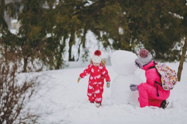 Mutlu aile kadın, oynarken, karlı park veya orman mekanlarda kardan adam yapma kış sıcak giysiler, küçük kız. Kış eğlence, dinlence tatil günlerinde. Aşk ilişki aile çocukluk yaşam tarzı kavramı